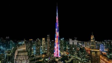 Night view of Burj Khalifa illuminated with colourful LED lights, surrounded by the glowing skyline of Downtown Dubai, UAE.