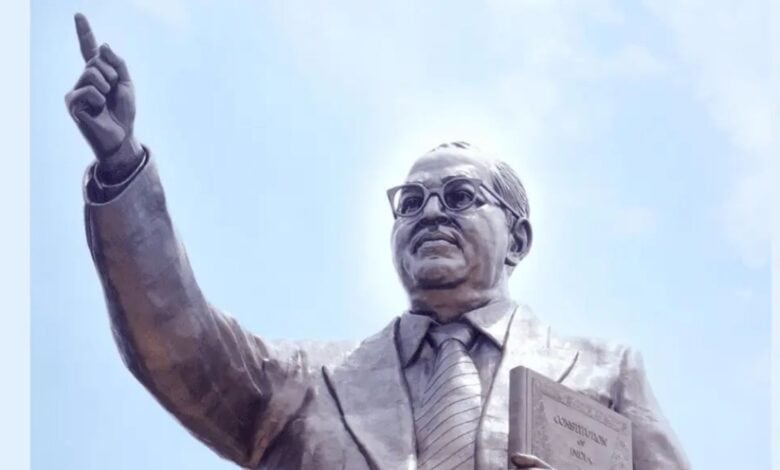 Statue of Dr. B.R. Ambedkar holding the Indian Constitution, pointing forward with vision and determination under a clear sky