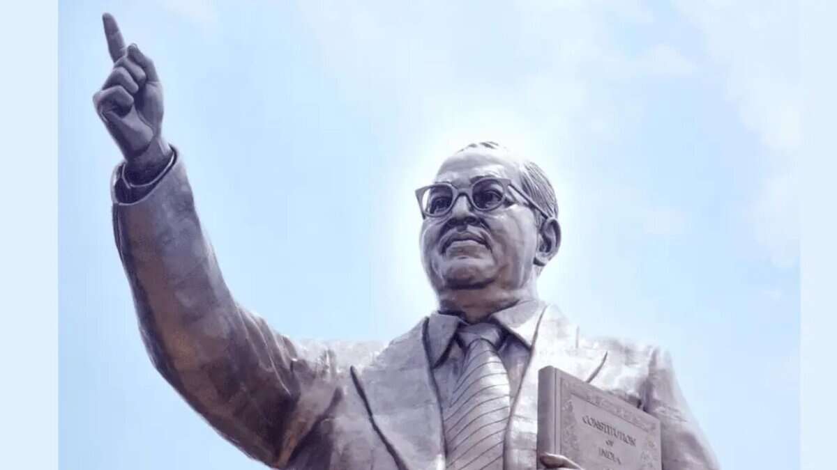 Statue of Dr. B.R. Ambedkar holding the Indian Constitution, pointing forward with vision and determination under a clear sky