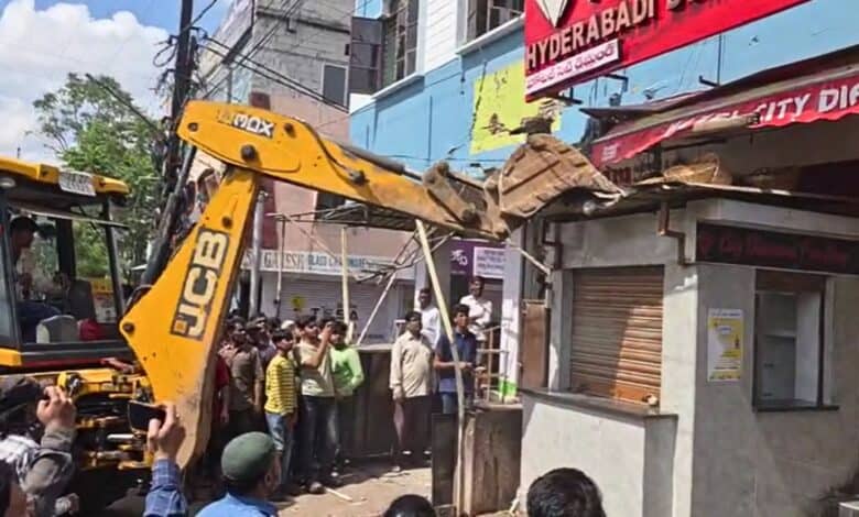 A GHMC JCB breaks down encroachments on the footpath in Asifnagar