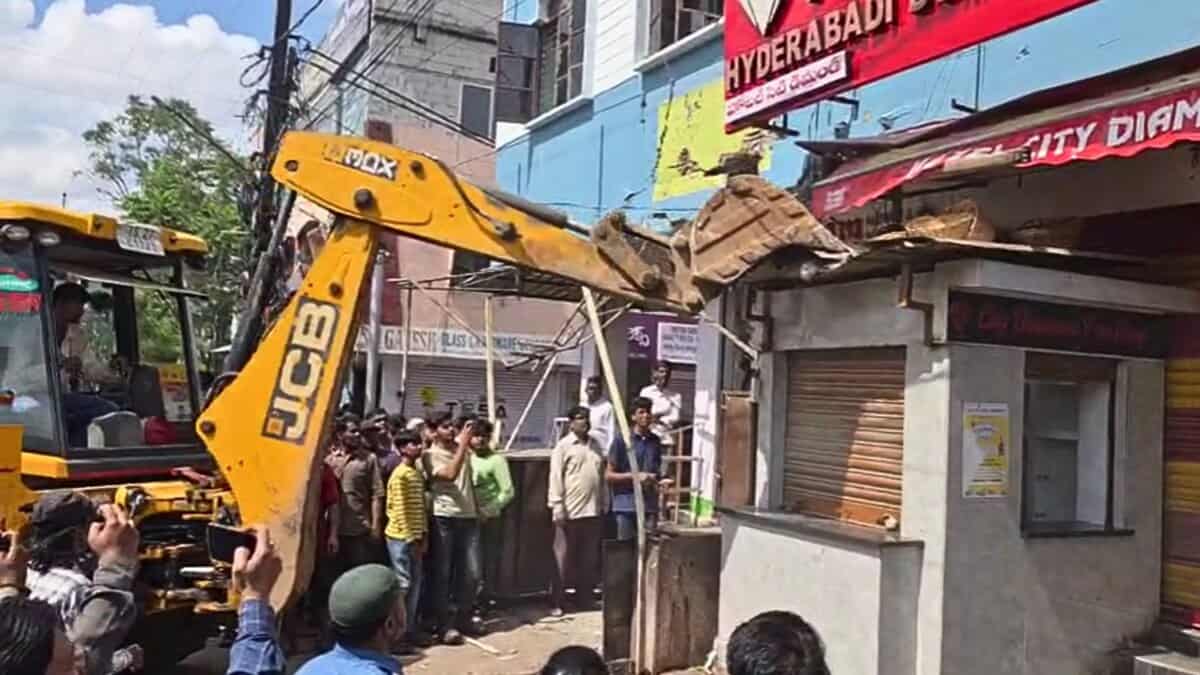 A GHMC JCB breaks down encroachments on the footpath in Asifnagar