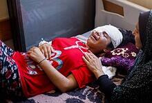 Injured Palestinian girl with bandaged eyes lies on a hospital bed in Gaza, comforted by a woman, during Israel’s ongoing assault on the Gaza Strip.