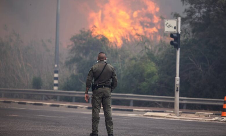 A security member stands while smoke and flame rise.