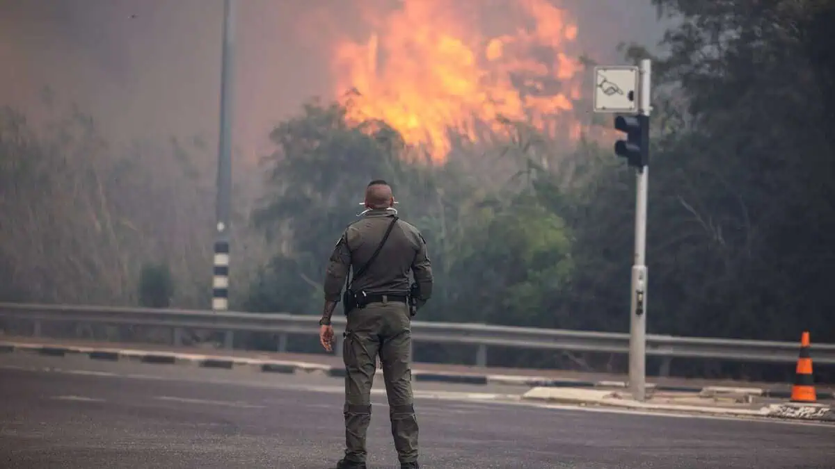 A security member stands while smoke and flame rise.