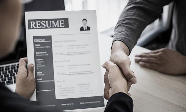 Representational Image of two men shaking hands while other one holds resume for jobs in Germany