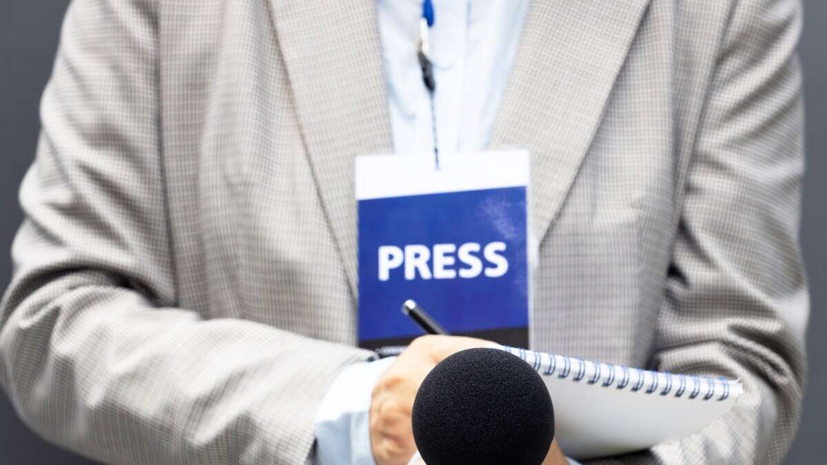 Representational Image of man wearing press ID and holding a mic