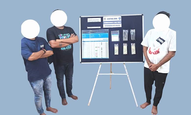 Accused with blurred faces seen standing near a table displaying seized cash and mobile phones in a cricket betting case.