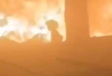 Palestinian girl silhouetted against flames inside a bombed classroom in Gaza