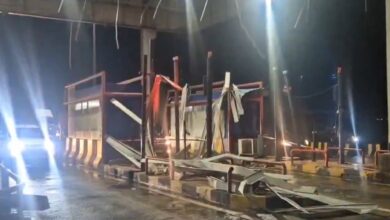 A collapsed toll gate roof in Siddipet, with a car attempting to pass by the debris after heavy rains and strong winds.
