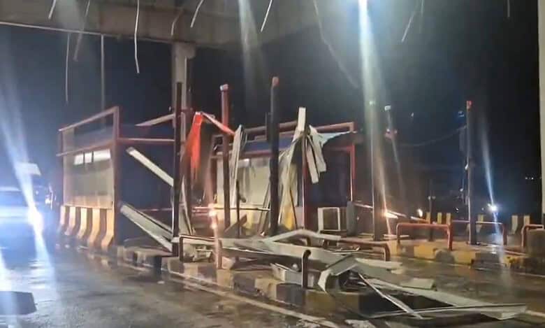 A collapsed toll gate roof in Siddipet, with a car attempting to pass by the debris after heavy rains and strong winds.