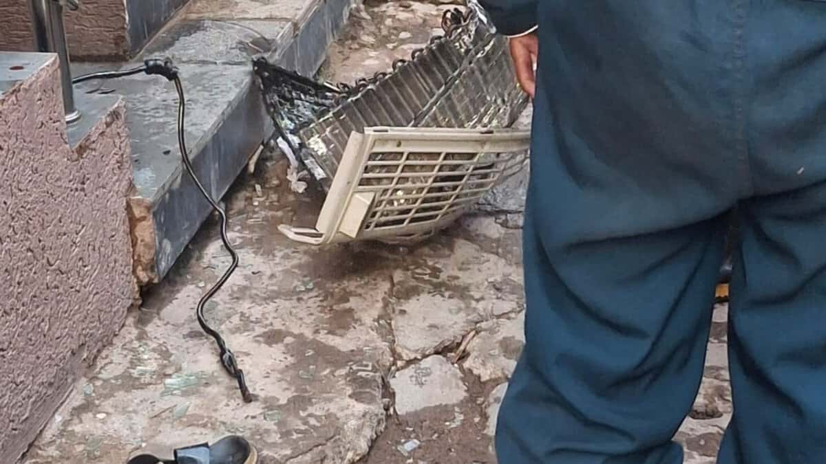 AC parts scattered on the floor with firefighters standing nearby responding to the aftermath of an AC blast in Talab Katta that injured two individuals