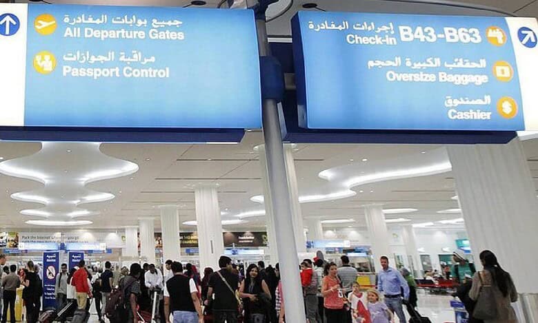 Travellers at Dubai International Airport near departure gates and check-in area.