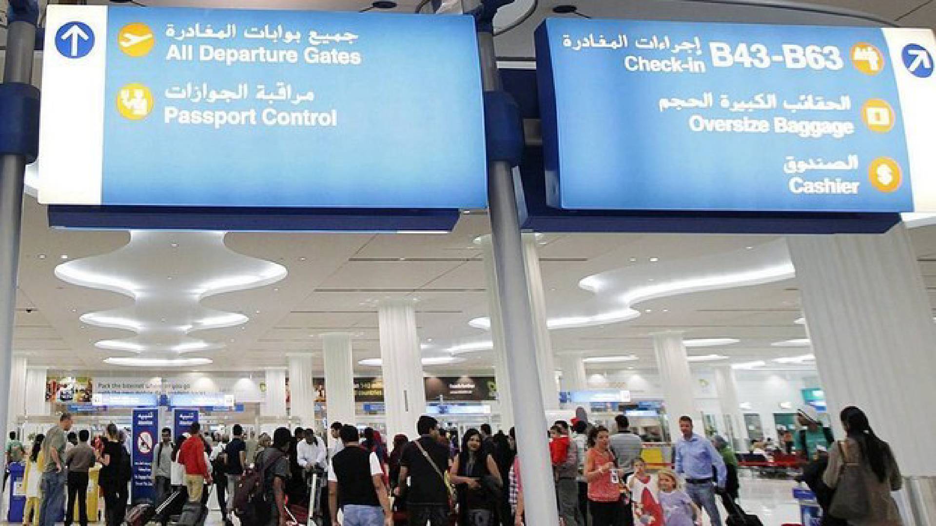 Travellers at Dubai International Airport near departure gates and check-in area.