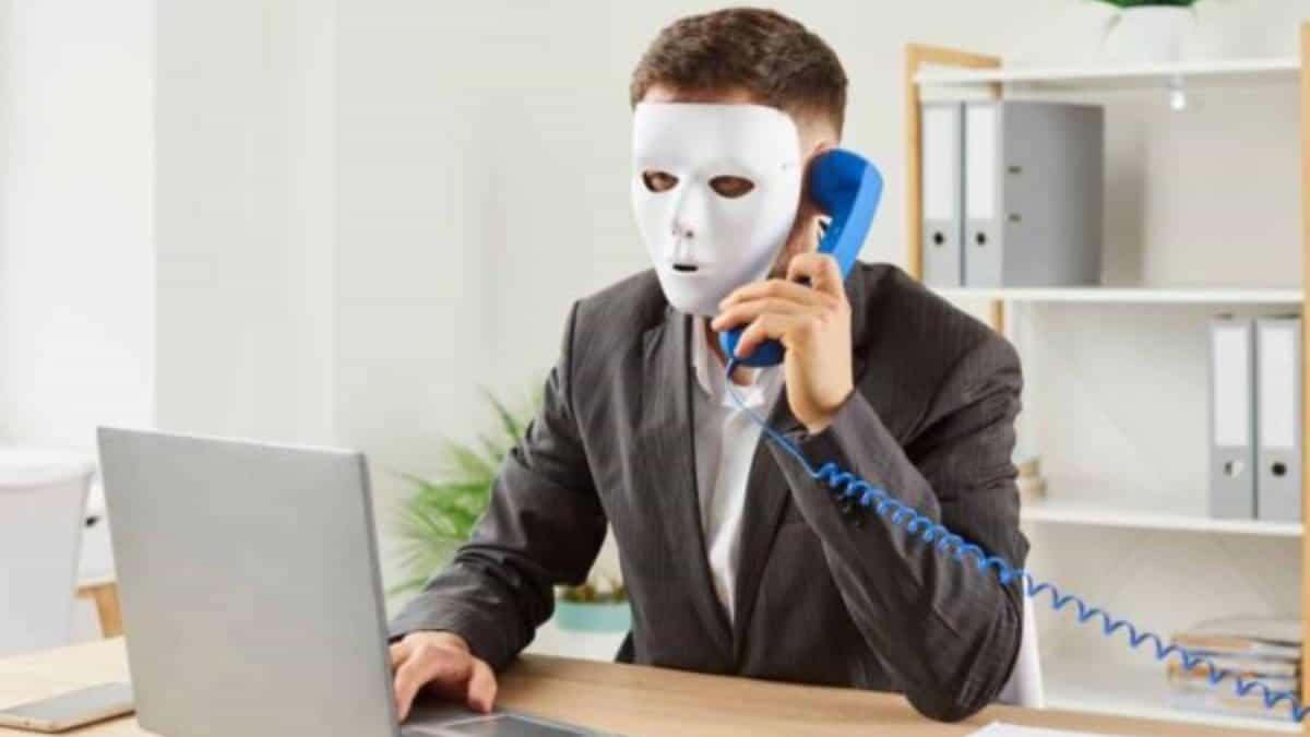 Representationa image of a man with a mask sitting with a laptop for job fraud in Hyderabad story
