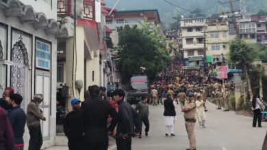 The image displays a picture of Nainital with police and a large number of right-wing protestors