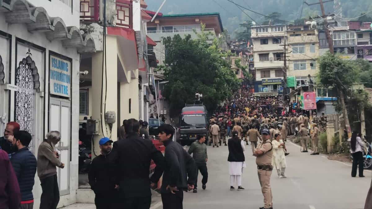 The image displays a picture of Nainital with police and a large number of right-wing protestors