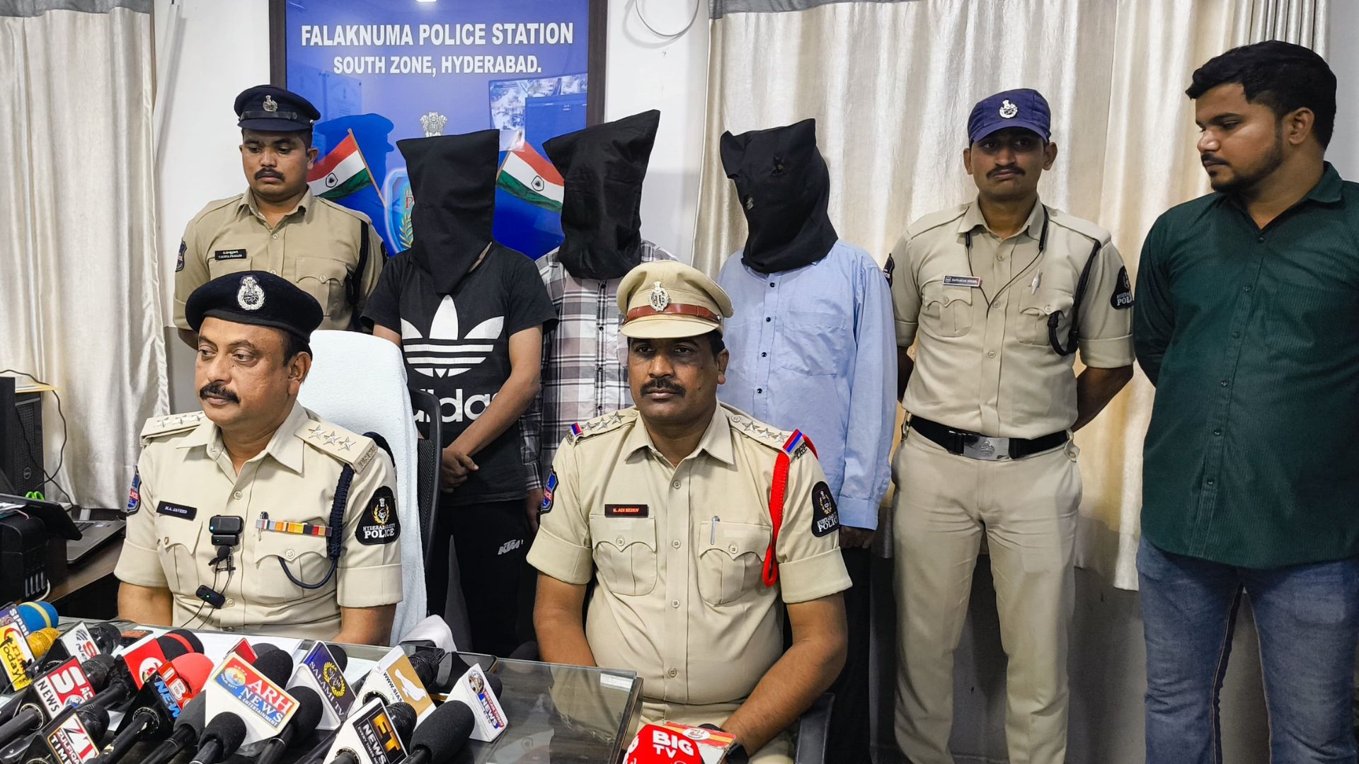 The image displays a picture of three men covered in black cloth and police officers