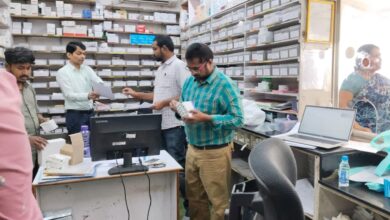 The image displays a picture of DCA officials conducting inspection at a pharmacy