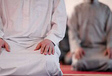 The image displays people offering namaz