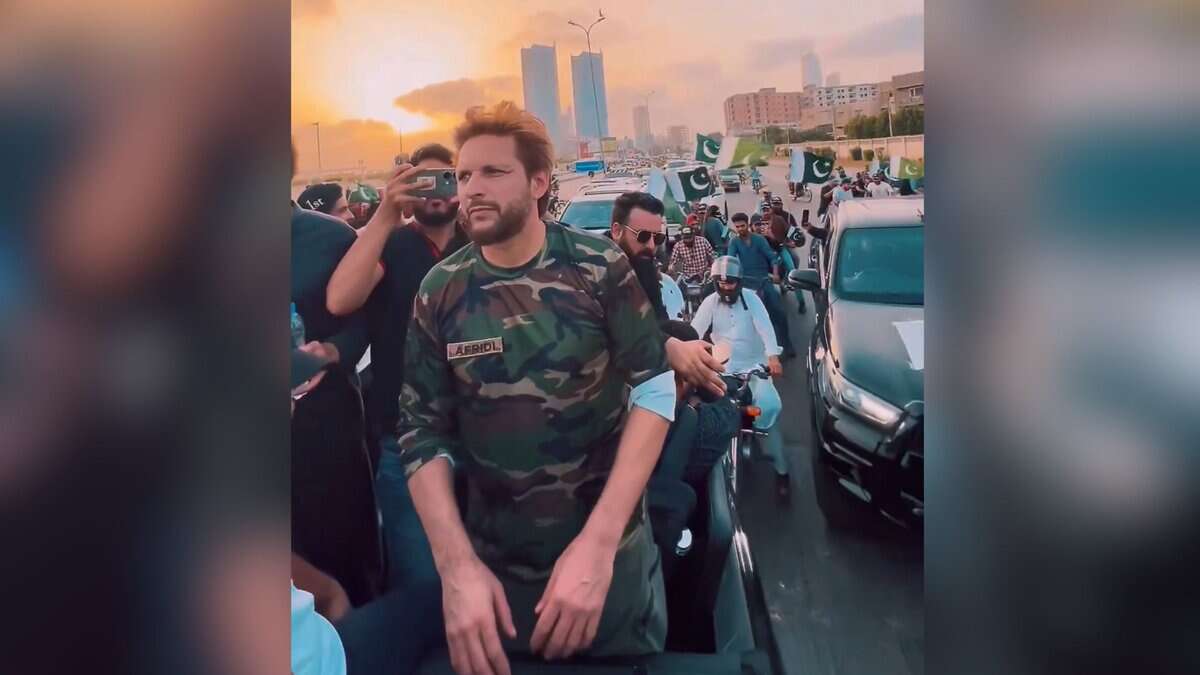 The image displays a picture of former cricketer Shahid Afridi participating in a 'victory' rally in Karachi