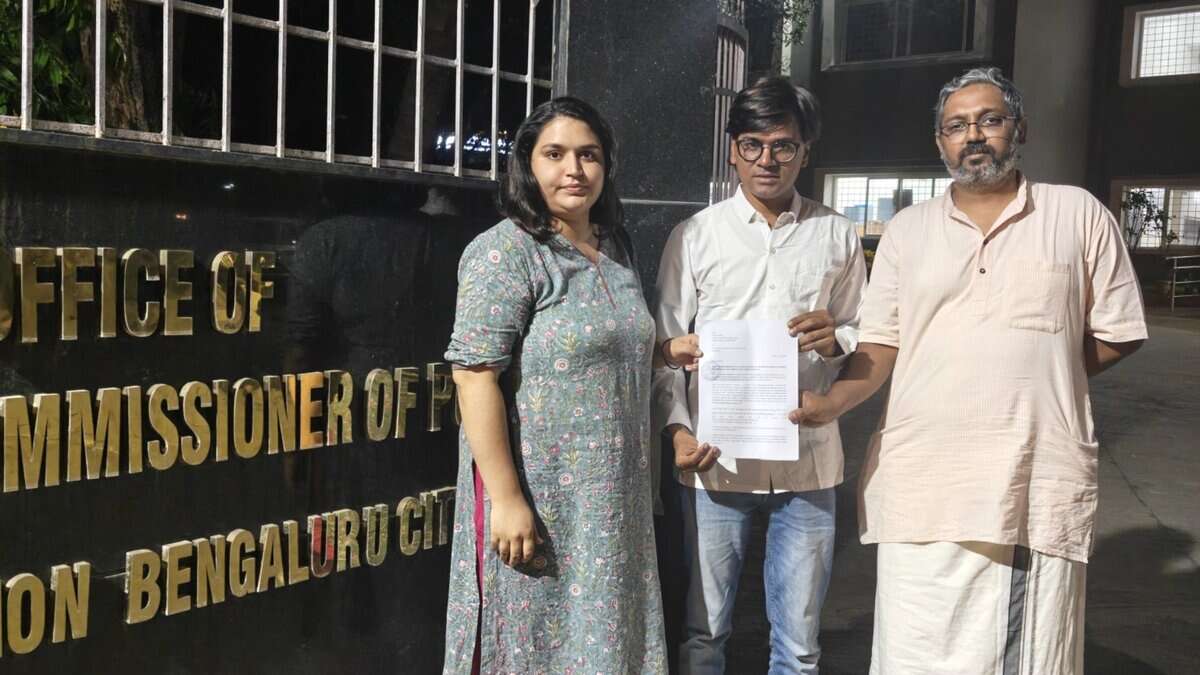 The image displays a picture of Alt News co founder and fact checker Mohammed Zubair in front of the office of Bengaluru police commissioner