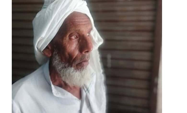 The image displays a picture of an elderly Muslim farmer