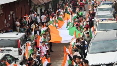 The image displays a picture of scores of people holding the national flag as part of the Tiranga Yatra