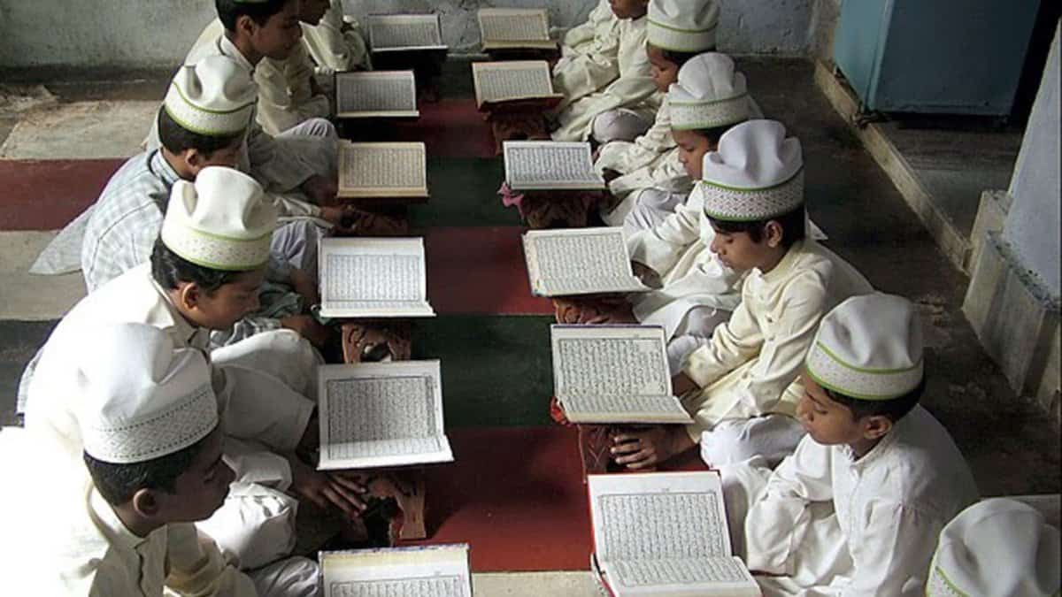 The image shows a madrasa with Muslim boys studying