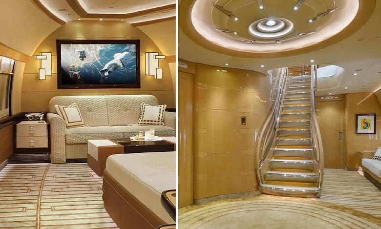 Luxurious interior of a customised Boeing 747-8 jet featuring a private lounge with a widescreen TV, plush seating, and a grand staircase with ambient lighting.