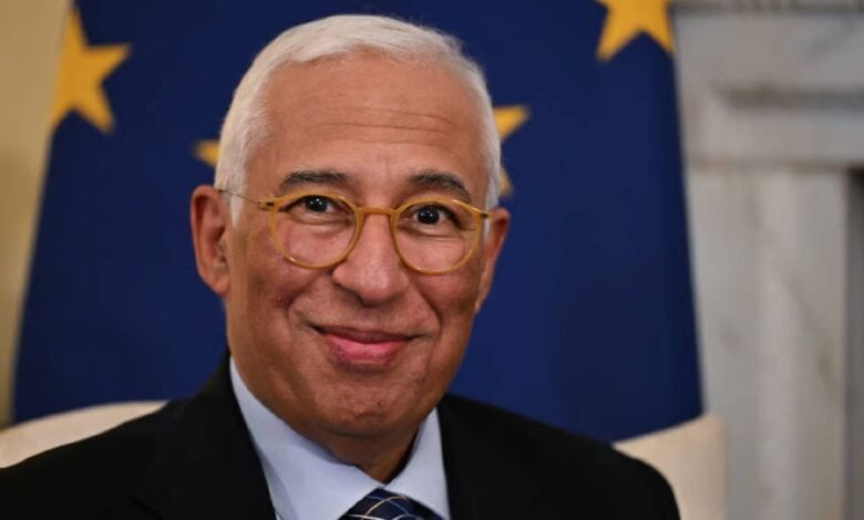 An older man with glasses and a tie smiling