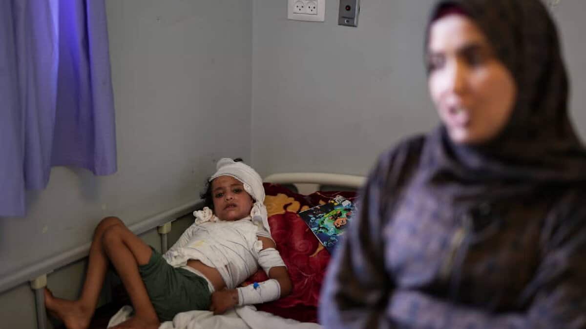 A young burns patient in Gaza lies in bed as his mother applies ointment to his injured body, carefully tending to his wounds.