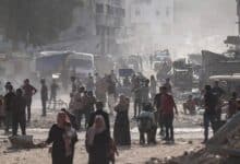 Civilians walk through a dusty, rubble-strewn street in Gaza’s Khan Younis.