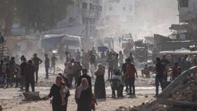 Civilians walk through a dusty, rubble-strewn street in Gaza’s Khan Younis.