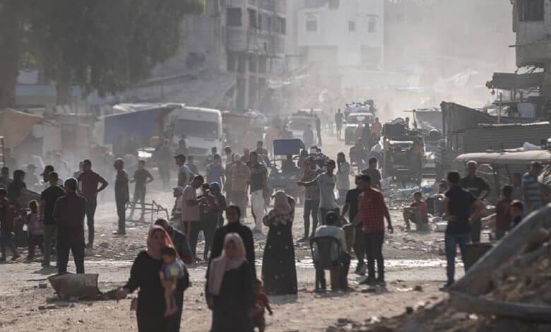 Civilians walk through a dusty, rubble-strewn street in Gaza’s Khan Younis.