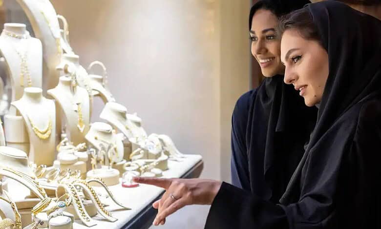 Two women in abayas admire gold jewellery displays at a shop in Dubai’s Gold Souk.