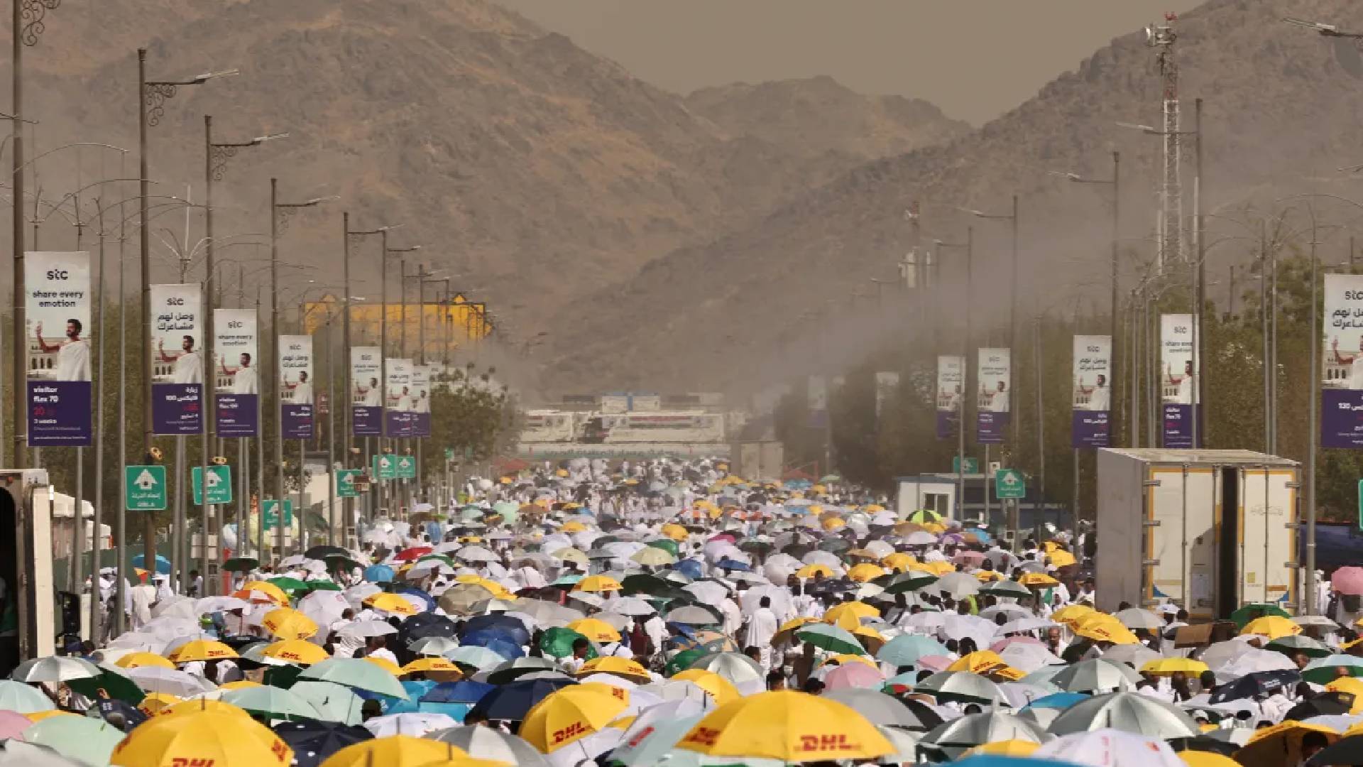 Pilgrims walk under colourful umbrellas during Haj 2024 in Saudi Arabia, braving the summer heat on their spiritual journey.