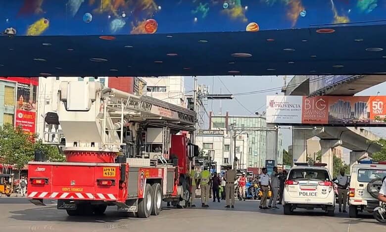 A scene at Cyber Tower Junction in Hyderabad during a mock air siren and civil defense drill. A fire truck with is parked on the left, while police vehicles and personnel manage the area