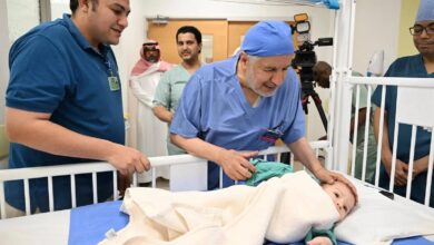 Mohammed Abdulrahman Juma, a Egyptian boy with a parasitic twin, lies in a hospital bed surrounded by a medical team in Saudi Arabia following a successful surgery.