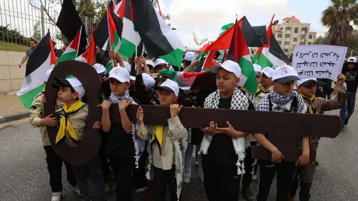 A group of Palestinian children march holding large cut-out keys, symbolising the homes their families were displaced from in 1948. Dressed in scout uniforms and keffiyehs, they carry Palestinian flags and placards during a Nakba Day demonstration.