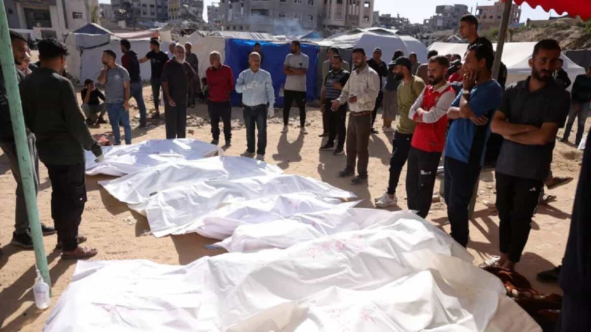 People gather around bodies of Palestinians wrapped in white shrouds after an Israeli airstrike in Gaza.