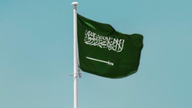 Saudi Arabian national flag waving on a clear blue sky background.