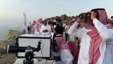 Group of Saudi astronomers and officials observe the sky with binoculars and telescopes from a mountaintop, looking for the crescent moon to mark the beginning of a new Islamic month.
