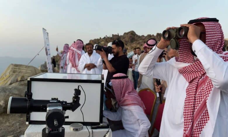 Group of Saudi astronomers and officials observe the sky with binoculars and telescopes from a mountaintop, looking for the crescent moon to mark the beginning of a new Islamic month.