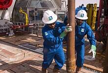 Saudi Aramco workers operate drilling equipment at an oil rig site.