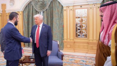 US President Donald Trump shakes hands with the interim Syrian President during a formal meeting in Saudi Arabia, as a Saudi Crown Prince observes from the side.