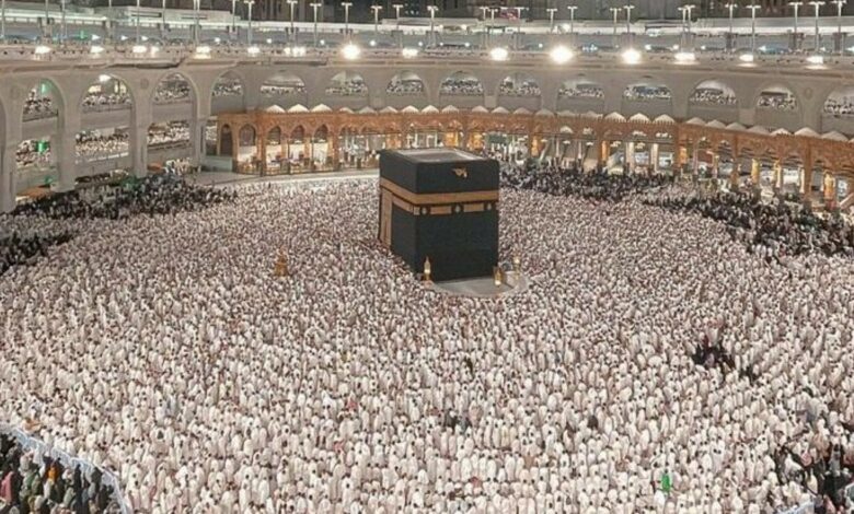 Thousands of Muslim pilgrims performing Umrah around the Kaaba at the Grand Mosque in Makkah, Saudi Arabia, during the night under bright lights and towering hotel buildings.