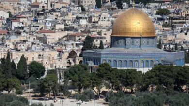 A view of Al-Aqsa Mosque with its golden Dome of the Rock, surrounded by historic stone buildings and trees in occupied East Jerusalem.