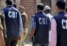 The image of a CBI officers, wearing jackets marked "CBI", are seen entering a premises accompanied by local police personnel during an official investigation.