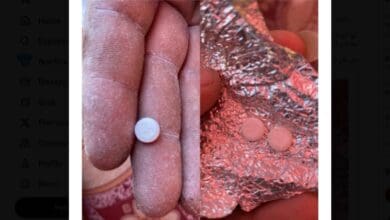 A close-up shows flour-dusted fingers holding a small round tablet marked "80", alongside another image of two similar Oxycodone pills on crumpled foil. The tablets appear coated with flour, suggesting they were found inside aid supplies.
