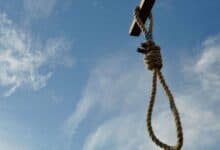 The image of a noose hanging from a wooden beam against a blue sky, symbolising execution.